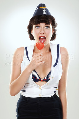 Buy stock photo Portrait, surprise and sailor woman with lollipop in studio isolated on a white background. Candy, wow and shocked air hostess with sugar food, heart sweets or travel dessert for vintage pin up girl