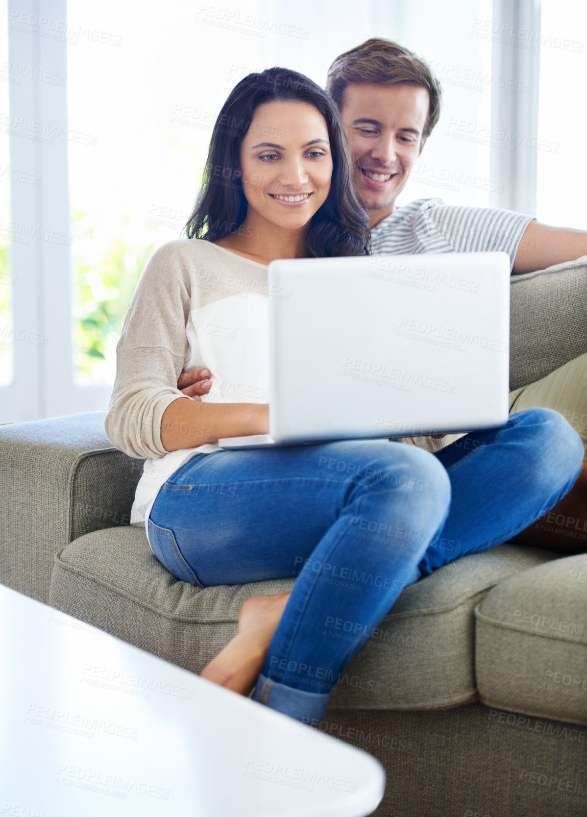 Buy stock photo A young couple using their laptop while sitting on the sofa at home