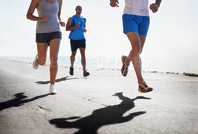Buy stock photo People, legs and running at beach for exercise, fitness or outdoor workout together on asphalt or road. Closeup of athletic group or runners in sports, teamwork or cardio training by the ocean coast