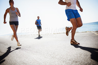 Buy stock photo People, team and running at beach for cardio, fitness or outdoor workout together on asphalt or road. Athletic group or runners in sports, training exercise or street on sunny day by the ocean coast