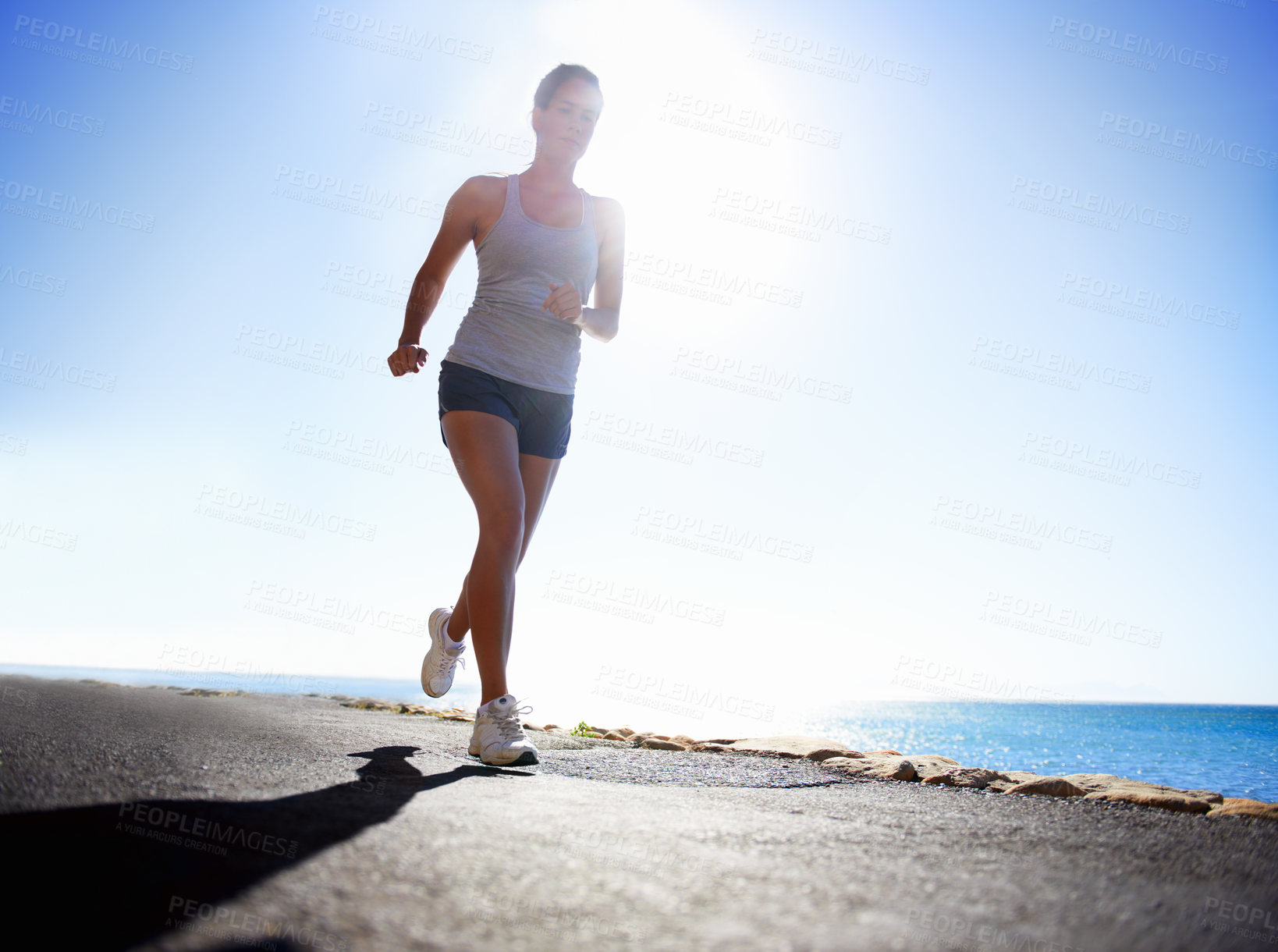 Buy stock photo Woman, fitness and running on beach for workout, exercise or outdoor training on a sunny day. Female person, athlete or runner in race, sprint or sports marathon on asphalt, road by the ocean coast