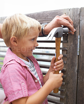Buy stock photo Happy, hammer and boy kid doing maintenance on wood gate for fun or learning. Smile, equipment and young child looking and working on repairs with tool for home improvement outdoor at modern house.