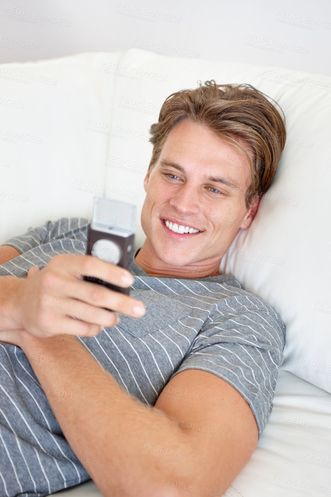 Buy stock photo Phone, smile and man relax on a sofa with social media, chat or texting while streaming in his home. Smartphone, reading and male person search for online dating, meme or web, gif or subscription