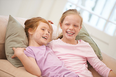 Buy stock photo Girl children, sisters and laughing on couch, bonding with love and care at family home, trust and support. Friends, comedy and time together in lounge, relax on sofa with happiness and positivity