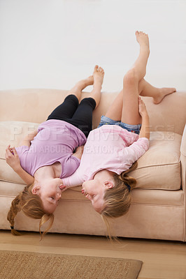 Buy stock photo Tongue out, sisters or upside down on couch for love, bond or care to relax in a fun family home. Friends, children or girl siblings on sofa in lounge together to play games with freedom or kids