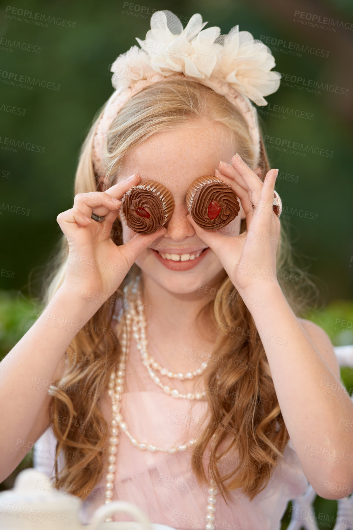 Buy stock photo Child, cupcakes and eyes or play smile or dress up in garden for birthday celebration, dessert or event. Female person, fancy accessories and funny face with sweet food or outdoor, quirky or humor