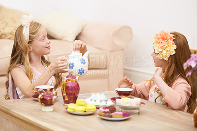Buy stock photo Girls, friends and playing tea party in home for fancy dress up fantasy for game, bonding or birthday. Female people, siblings and flower crown or pot for drinking or eat macarons, snack or chatting