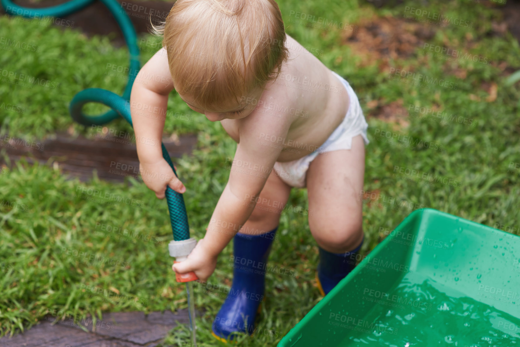 Buy stock photo A baby boy in his nappy and gumboots watering the garden