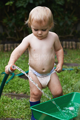 Buy stock photo Baby, playing with hose and gardening, water and  development with bucket, curiosity and backyard. Toddler, child and infant in garden, alone and childhood for skills, milestone and coordination