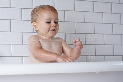 Buy stock photo Baby, child and playing with bubbles in bath of water for morning routine, skincare and wellness at home. Happy boy, kid and cleaning in tub with soap, foam and washing for fun, hygiene and bathroom