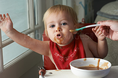 Buy stock photo A young baby boy eating to his hearts content in his high chair