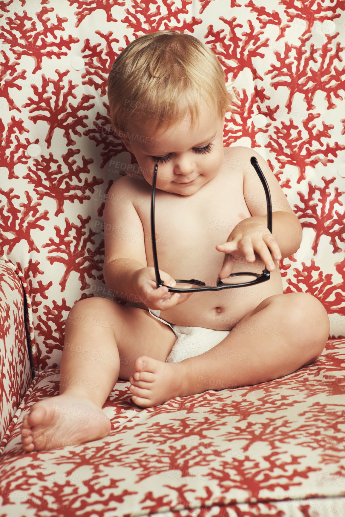 Buy stock photo Happy baby, blonde boy and playing with glasses on sofa in growth, youth or development in living room at home. Cute, adorable or little toddler, kid or child smile with innocent or positive attitude