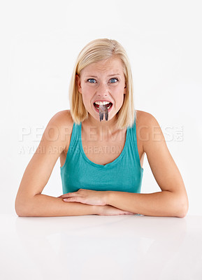 Buy stock photo Woman, portrait and eating a fish, tail or strange food in mouth on white background of studio. Crazy, diet and person with weird seafood, cuisine and face of disgust for taste of tuna or salmon