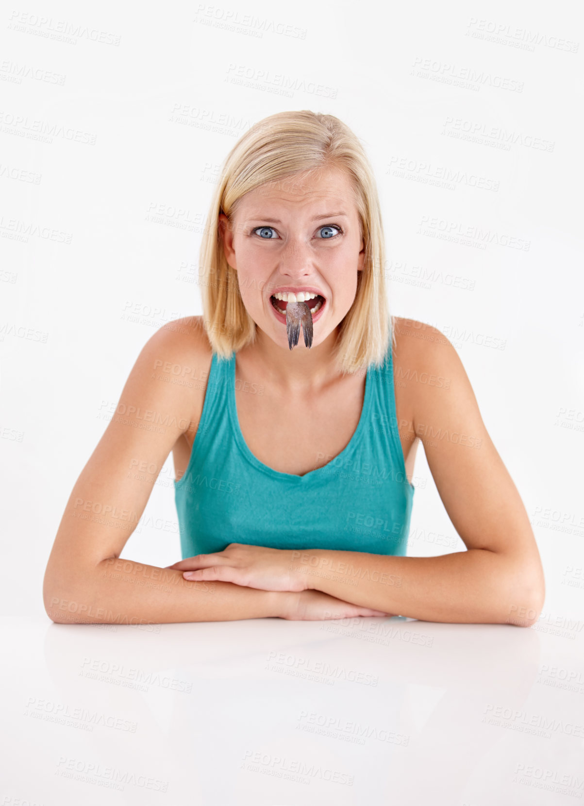 Buy stock photo Woman, portrait and eating a fish, tail or strange food in mouth on white background of studio. Crazy, diet and person with weird seafood, cuisine and face of disgust for taste of tuna or salmon