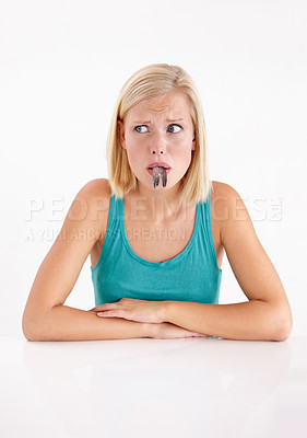 Buy stock photo A young woman pulling a face with a fish in her mouth