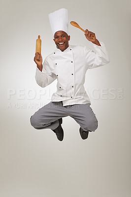 Buy stock photo Jumping, happy chef and studio with kitchen utensils,  career success and celebration in hospitality job. Black man, face and smile in small business in pride and white uniform by grey background