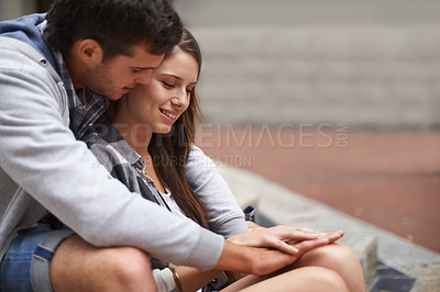 Buy stock photo A happy young couple sitting outside having an intimate moment