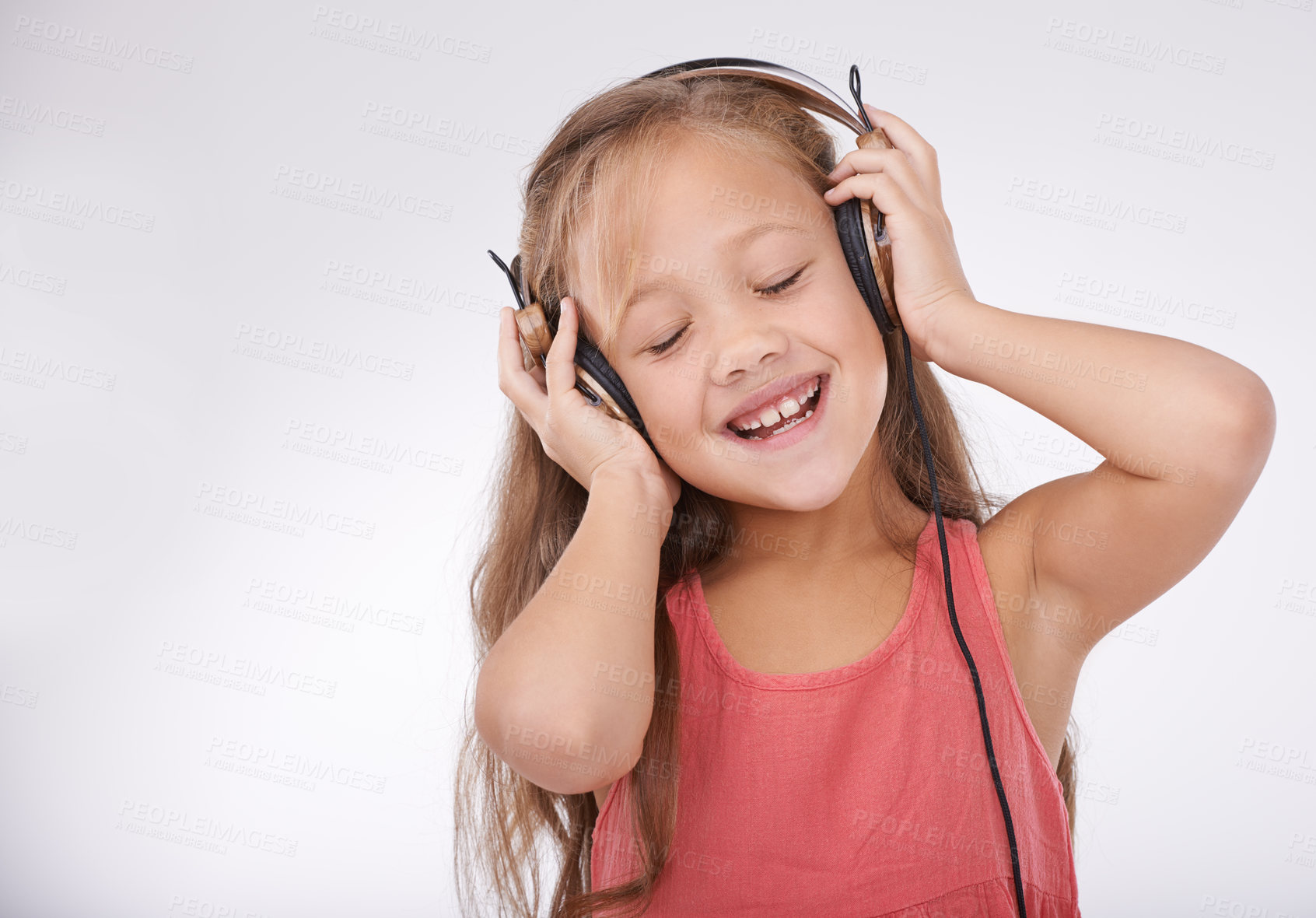 Buy stock photo Girl kid, music and happy with headphones in studio for audio, subscription and streaming multimedia on white background. Child, smile and listening to podcast, hearing sound and radio connection 