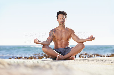 Buy stock photo A young man meditating next to the ocean