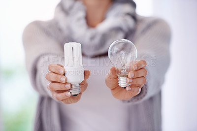 Buy stock photo A cropped image of a woman holding two different lightbulbs