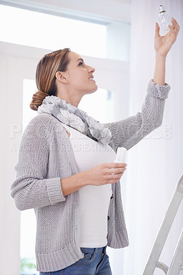 Buy stock photo Woman, change lightbulb and ladder in home for thinking, decision or choice for sustainable electricity. Person, light and power saving globe for ecology, climate change or care for product in house