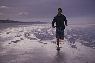 Buy stock photo A handsome young man exercising on the beach in the early morning