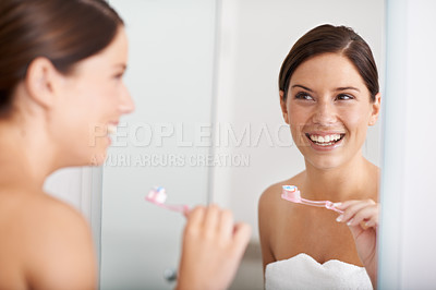 Buy stock photo A young woman standing in front of the mirror brushing her teeth