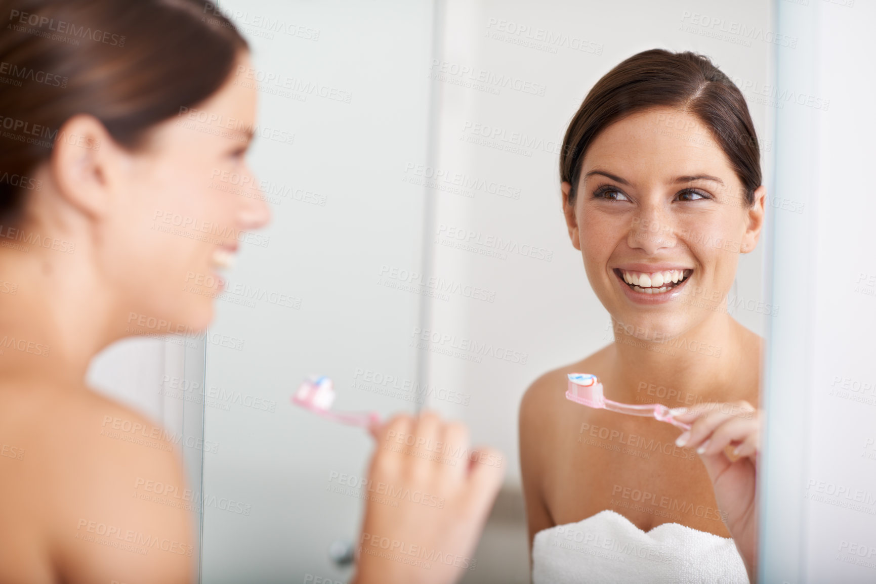 Buy stock photo A young woman standing in front of the mirror brushing her teeth