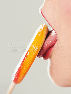 Buy stock photo Cropped shot of a woman licking a lollipop