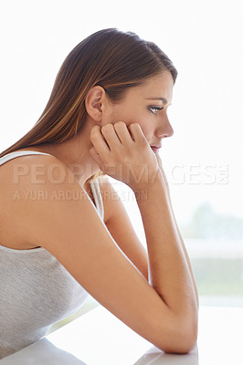 Buy stock photo Profile shot of an attractive young woman sitting and looking thoughtful