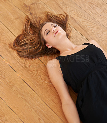 Buy stock photo Shot of a n attractive young woman lying on the floor with her eyes closed