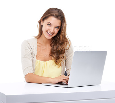 Buy stock photo Studio shot of an attractive young woman sitting at a table and using a laptop
