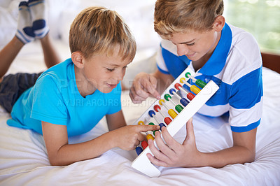 Buy stock photo Children, home and playing with abacus for learning, happy and bonding together with educational for math. Brother, teaching and counting game on bed with sibling love, care and development in house