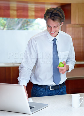 Buy stock photo Laptop, apple and business man in home for morning routine, email and healthy breakfast. Professional, worker and person on computer for website, research and internet in house kitchen with fruit