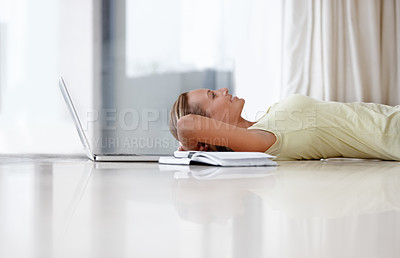 Buy stock photo A young woman lying on her floor at home next to her laptop and a notebook