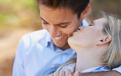 Buy stock photo Happy couple, kiss and hug in nature for embrace, love or support in outdoor walk or bonding. Young woman and man with smile on cheek for affection, comfort or romance in forest or woods together