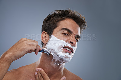 Buy stock photo Man, shaving and frustrated with razor in studio portrait for wellness, skin and grooming by grey background. Person, model and stress with beard, facial hair removal and product for cosmetic change
