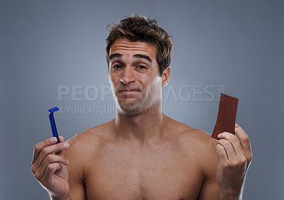 Buy stock photo Man, hair removal and choice with doubt, razor and beauty with decision and studio background with options and products. Face, wellness or model shaving for skincare, routine treatment and sand paper