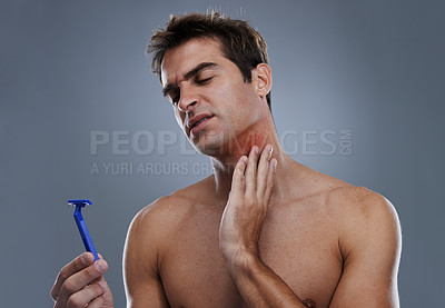 Buy stock photo Man, shaving and beard or razor pain for hair removal or red rash, inflammation or grey background. Male person, tool and cleaning in studio or accident for wellness maintenance, burn or mockup space