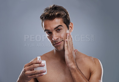 Buy stock photo Portrait, cream and man with skincare, wellness and beauty with lotion and moisture with glow and bottle on a grey studio background. Portrait, person and model with grooming routine and treatment