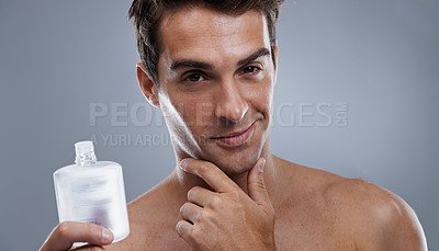 Buy stock photo Studio shot of a handsome young man applying aftershave to his face