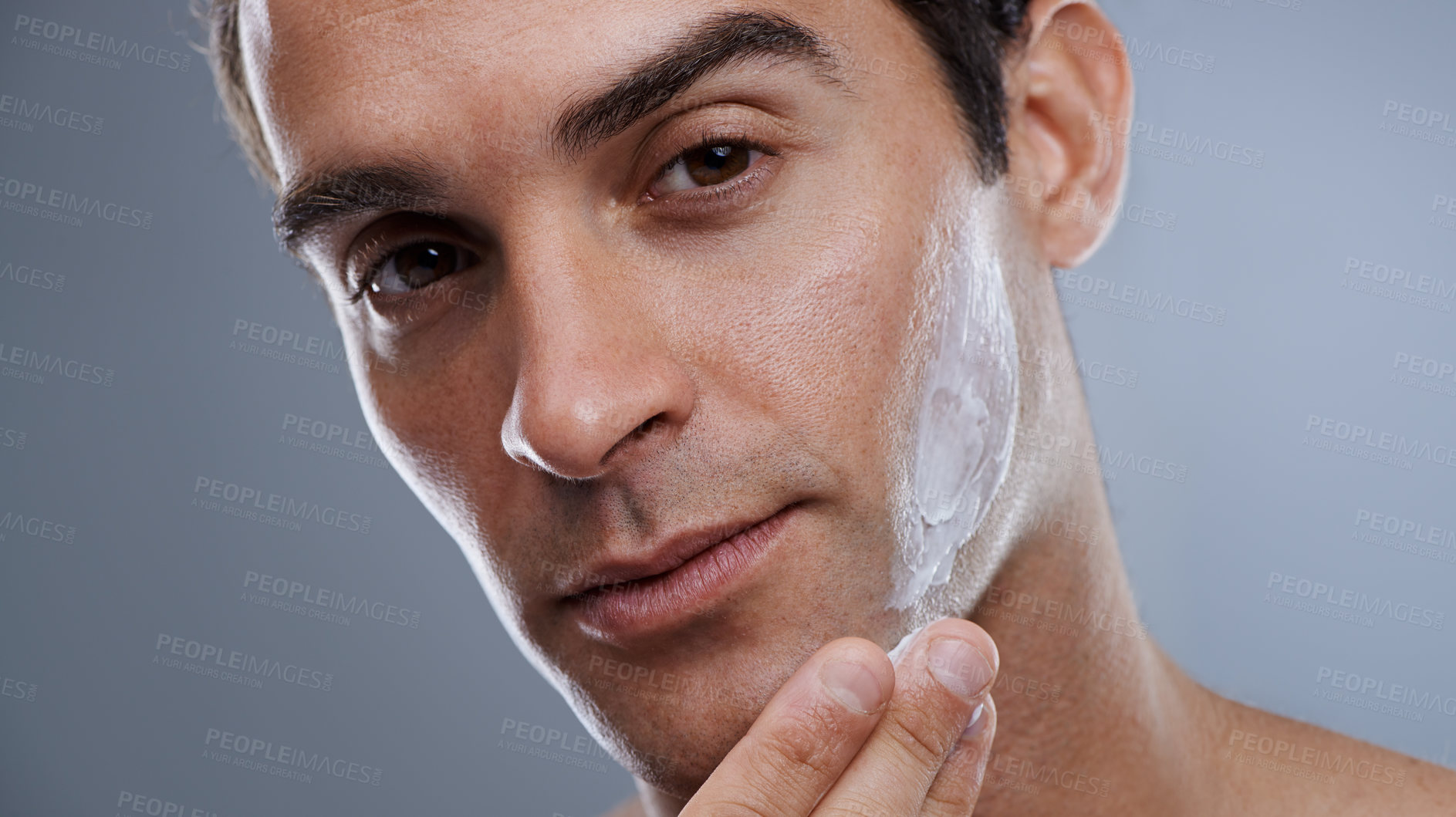 Buy stock photo Portrait, cream and man with dermatology, cosmetics and beauty on a grey studio background. Portrait, person and model with grooming routine or skincare with lotion or moisture after shave with shine