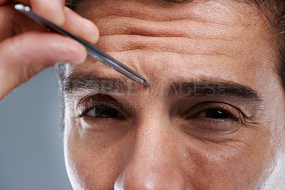 Buy stock photo Man, portrait and tweezers for eyebrows in studio or face grooming, hygiene or grey background. Male person, tools and painful hair removal for healthy morning routine or cosmetics, treatment or care