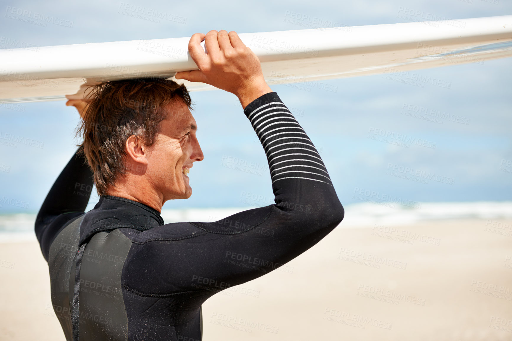 Buy stock photo Shot of a smiling young surfer at the beach carrying his board on his head
