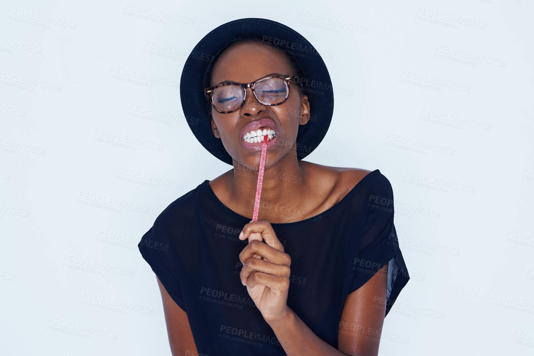 Buy stock photo Face, fashion and black woman eating candy in studio on white background for sugar craving. Food, glasses and biting sweets with young african model eyes closed for appetite, greed or hunger