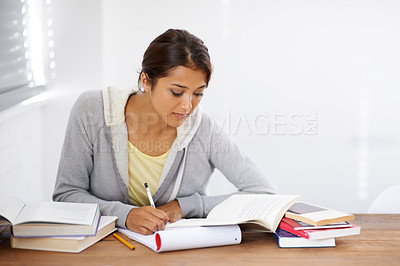 Buy stock photo Serious, writing and student studying in college, learning and work on school project at desk. Reading, books and woman at table for education, knowledge and info on notepad in university in Brazil