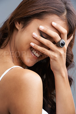 Buy stock photo Beauty, funny and shy face of woman with hand in studio on gray background for comedy, humor or joke. Skincare, smile and laughing with embarrassed young model at salon or spa for hair care treatment