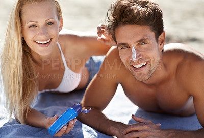 Buy stock photo Love, portrait and sunscreen with happy couple on beach blanket for date, bonding and tropical holiday. Romance, man and woman with cream, skincare and relax together with travel and adventure.