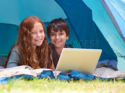 Buy stock photo Children, portrait and happy with laptop for camping in tent, social media or online movie with vacation in nature. Family, face and siblings or smile outdoor on grass for trip, relax and holiday fun