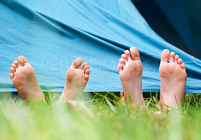 Buy stock photo Low-angle view of two children lying barefoot under a tent